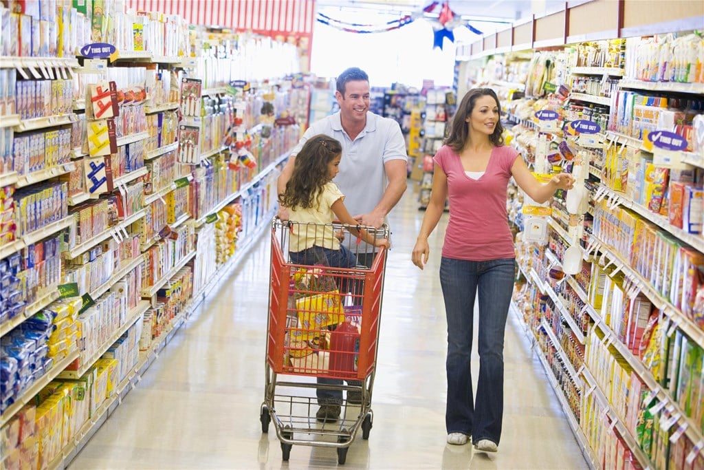 A family of 3 walking down an aisle in a grocery store