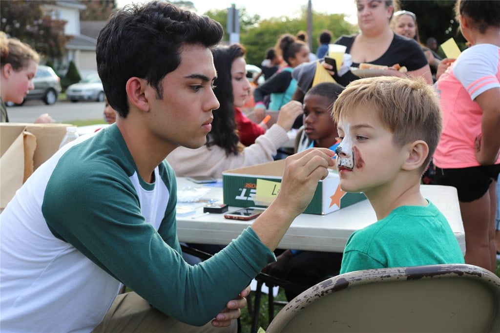 A boy having his face painted like an animal