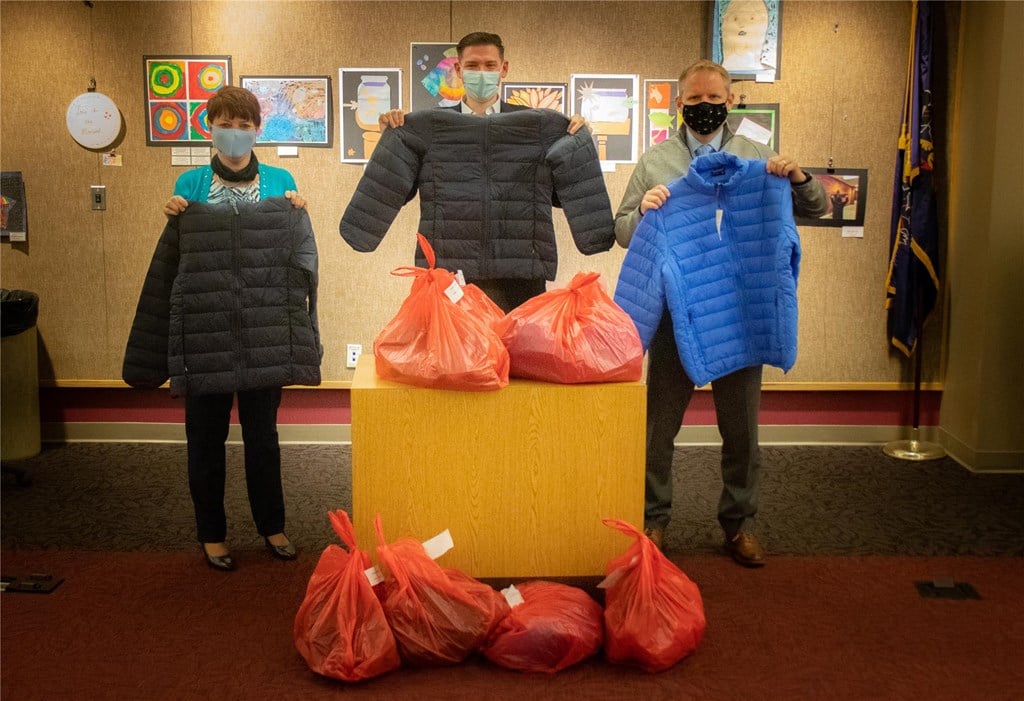 District administrators hold up donated coats.
